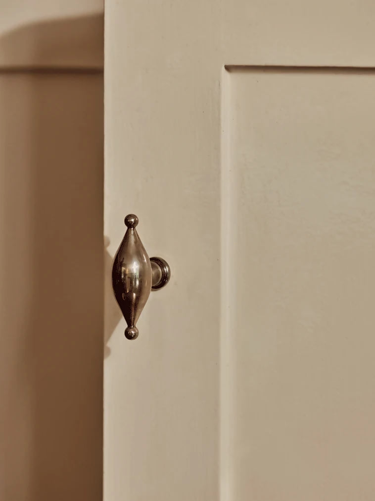 A gold-colored metal pull handle in an elliptical shape mounted on a white door, available  to buy on the-salon.com. SALON curates the finest , unique, handmade pieces from the interior industry's best makers and brands. Shop luxury furniture, lighting, rugs, art, antiques and vintage pieces and accessories from SALON interior designed rooms.