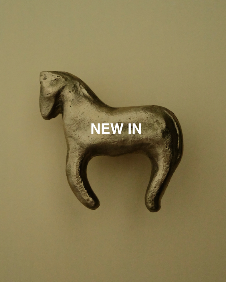 Bronze horse-shaped object with 'NEW IN' text on a beige background