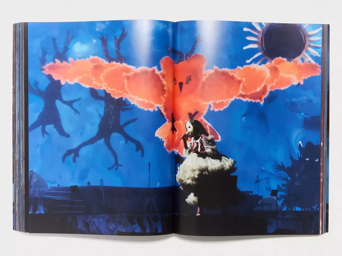 An image of a young girl wearing a mask and a filly white dress, with a fake large owl behind her, with its talons out.The background is ike a drawing out of a children's book with blues and darkness, available  to buy on the-salon.com. SALON curates the finest , unique, handmade pieces from the interior industry's best makers and brands. Shop luxury furniture, lighting, rugs, art, antiques and vintage pieces and accessories from SALON interior designed rooms.