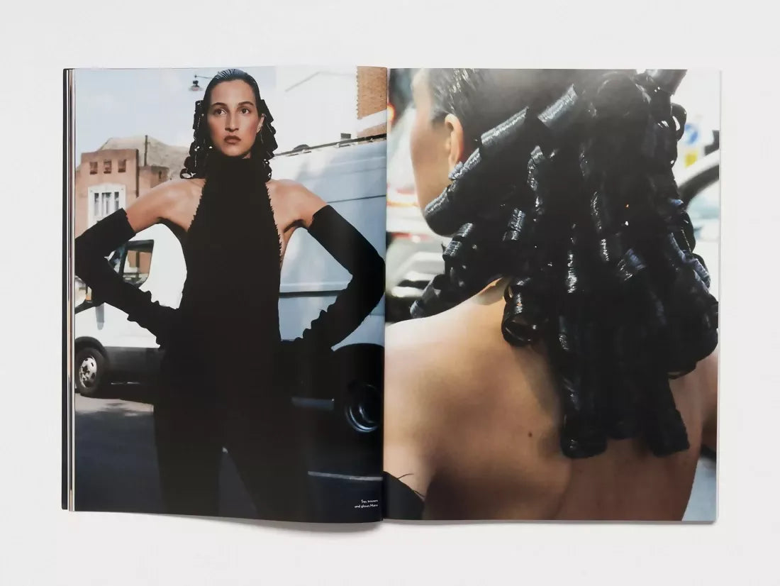 Open book, pages to a woman in black clothing holding a pose infant of a white transit van, the other side being a close up of her hair, gelled into curls, available  to buy on the-salon.com. SALON curates the finest , unique, handmade pieces from the interior industry's best makers and brands. Shop luxury furniture, lighting, rugs, art, antiques and vintage pieces and accessories from SALON interior designed rooms.