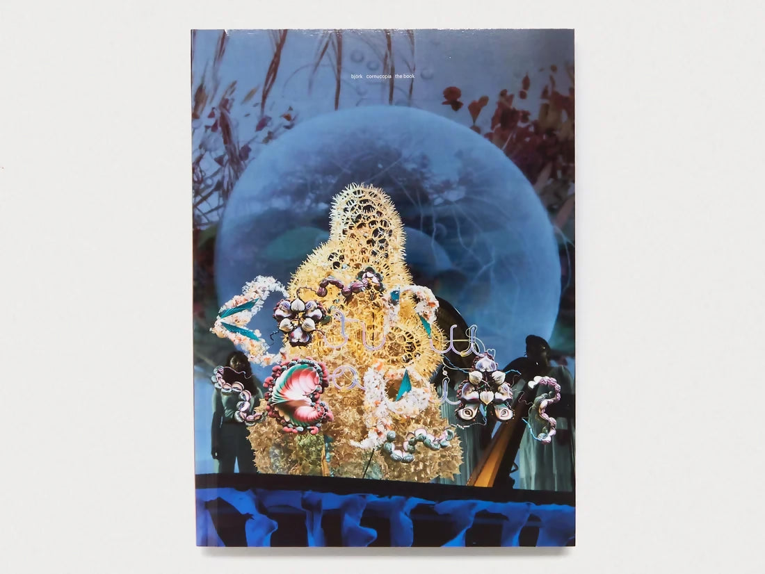 A cover image of the book 'CORNUCOPIA FROM ANTENNE BOOKS' featuring a theatrical setting with a large, intricate marionette puppet on stage under a spotlight, with elements of sets and costumes suggesting a futuristic or whimsical theme, available  to buy on the-salon.com. SALON curates the finest , unique, handmade pieces from the interior industry's best makers and brands. Shop luxury furniture, lighting, rugs, art, antiques and vintage pieces and accessories from SALON interior designed rooms.