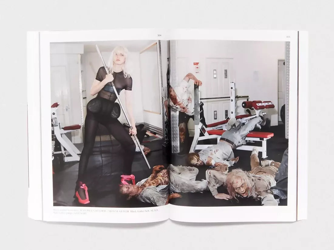 An image of an open book, containing a large image of a woman and zombie-like people in a gym setting,  available  to buy on the-salon.com. SALON curates the finest , unique, handmade pieces from the interior industry's best makers and brands. Shop luxury furniture, lighting, rugs, art, antiques and vintage pieces and accessories from SALON interior designed rooms.