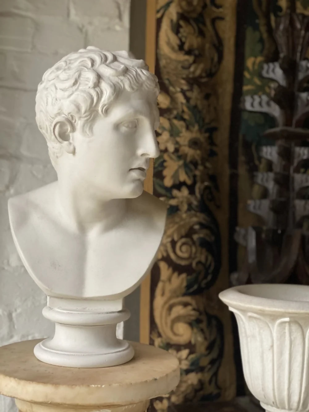 White marble bust on a pedestal with decorative wall in the background available to buy from the-salon.com. SALON curates the finest unique handmade pieces from the interior industry's best makers and brands. Shop luxury furniture, lighting, rugs, art, antiques and vintage pieces and accessories from SALON interior designed rooms.
