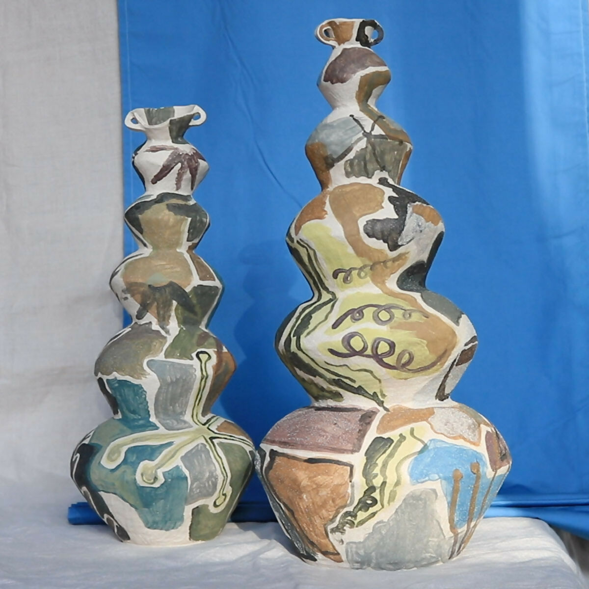 Two abstract ceramic vases on a blue background,  available  to buy on the-salon.com. SALON curates the finest , unique, handmade pieces from the interior industry's best makers and brands. Shop luxury furniture, lighting, rugs, art, antiques and vintage pieces and accessories from SALON interior designed rooms.