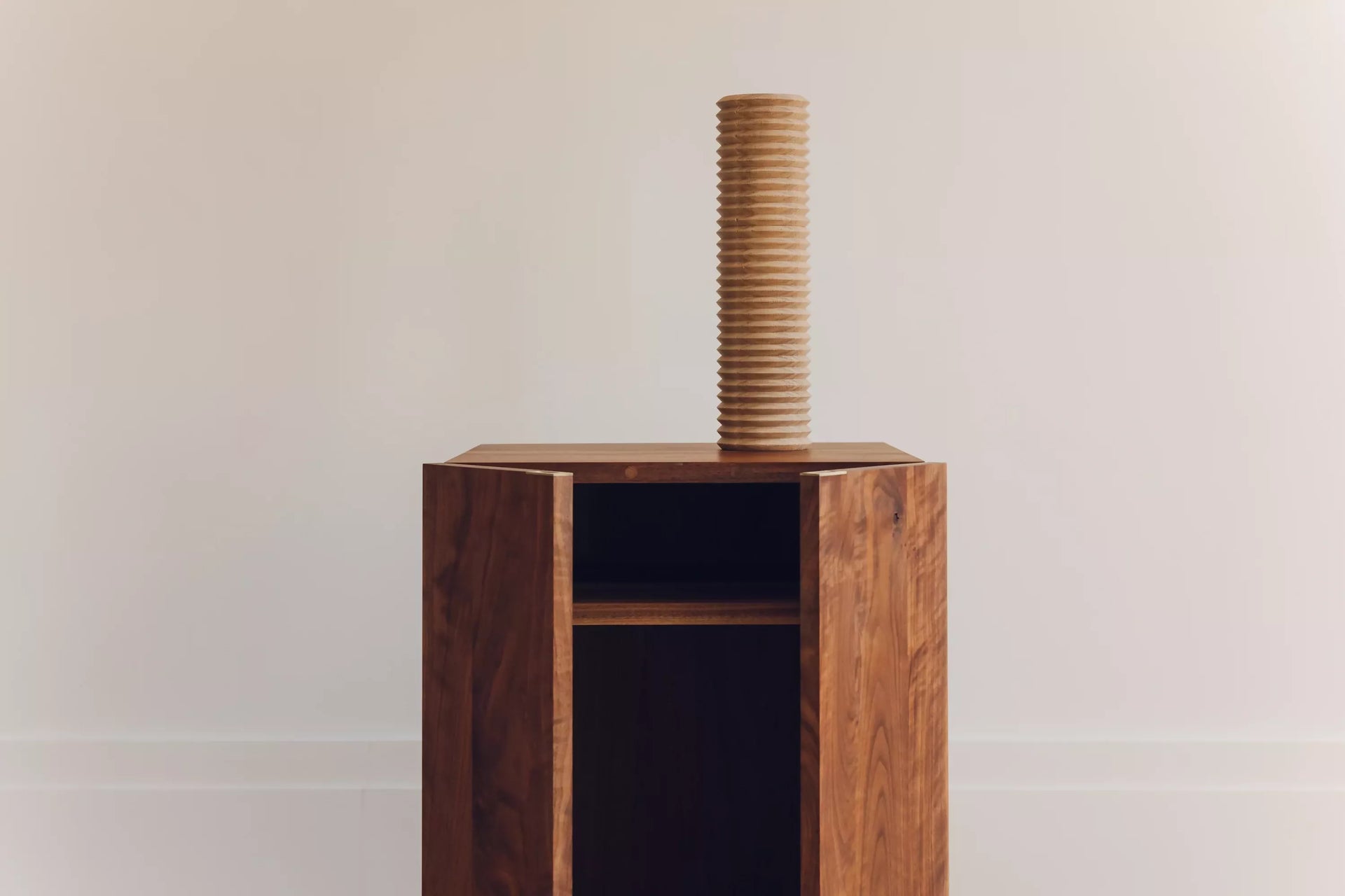 An image of the wooden cabinet, with open doors and a wooden tube on top,  available  to buy on the-salon.com. SALON curates the finest , unique, handmade pieces from the interior industry's best makers and brands. Shop luxury furniture, lighting, rugs, art, antiques and vintage pieces and accessories from SALON interior designed rooms.