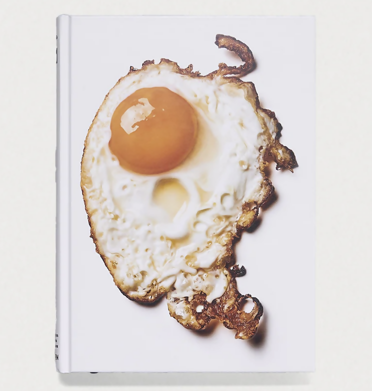 Book cover with a fried egg design on a white background, available  to buy on the-salon.com. SALON curates the finest , unique, handmade pieces from the interior industry's best makers and brands. Shop luxury furniture, lighting, rugs, art, antiques and vintage pieces and accessories from SALON interior designed rooms.