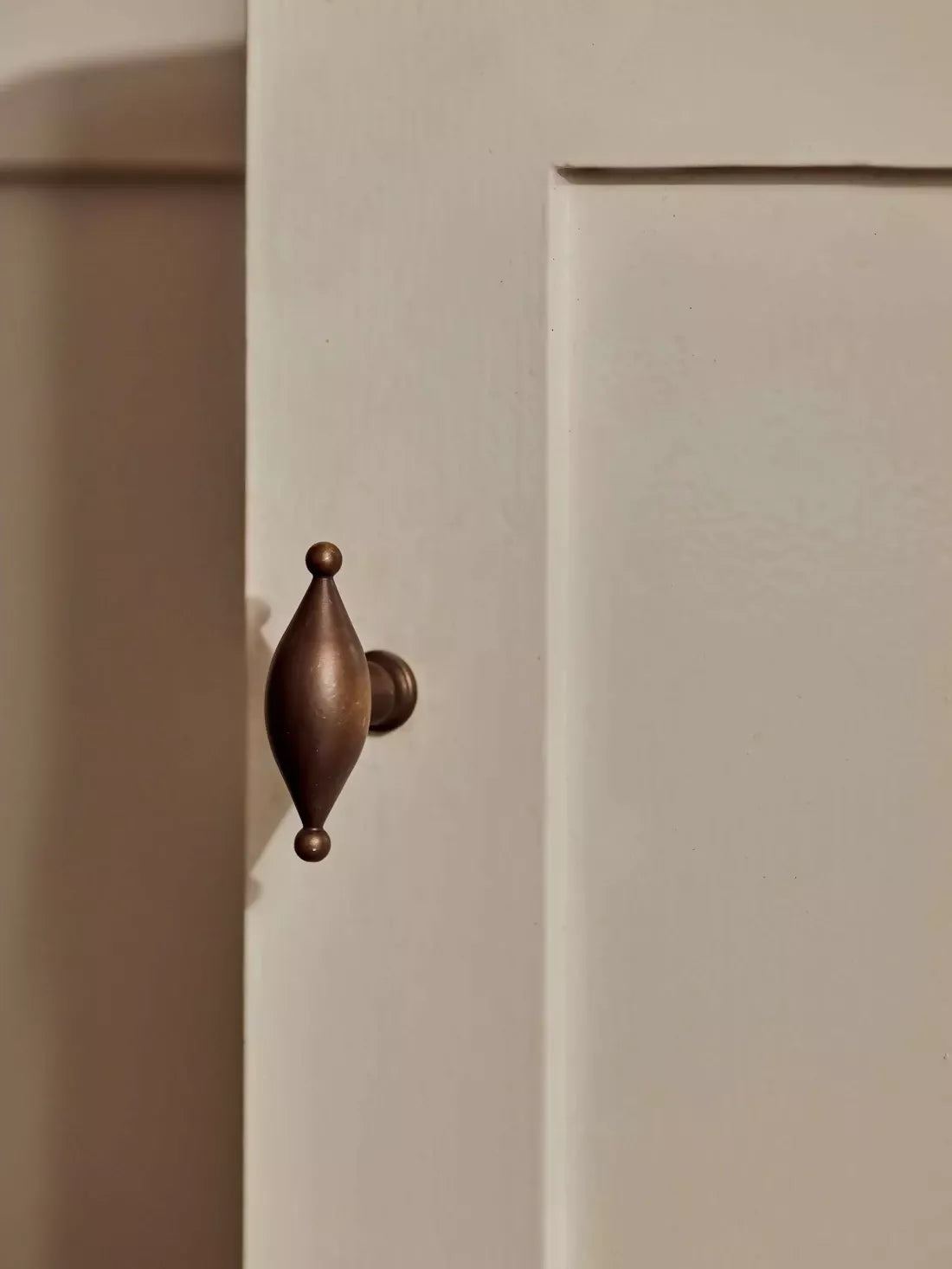 A gold-colored metal pull handle in an elliptical shape mounted on a white door, available  to buy on the-salon.com. SALON curates the finest , unique, handmade pieces from the interior industry's best makers and brands. Shop luxury furniture, lighting, rugs, art, antiques and vintage pieces and accessories from SALON interior designed rooms.