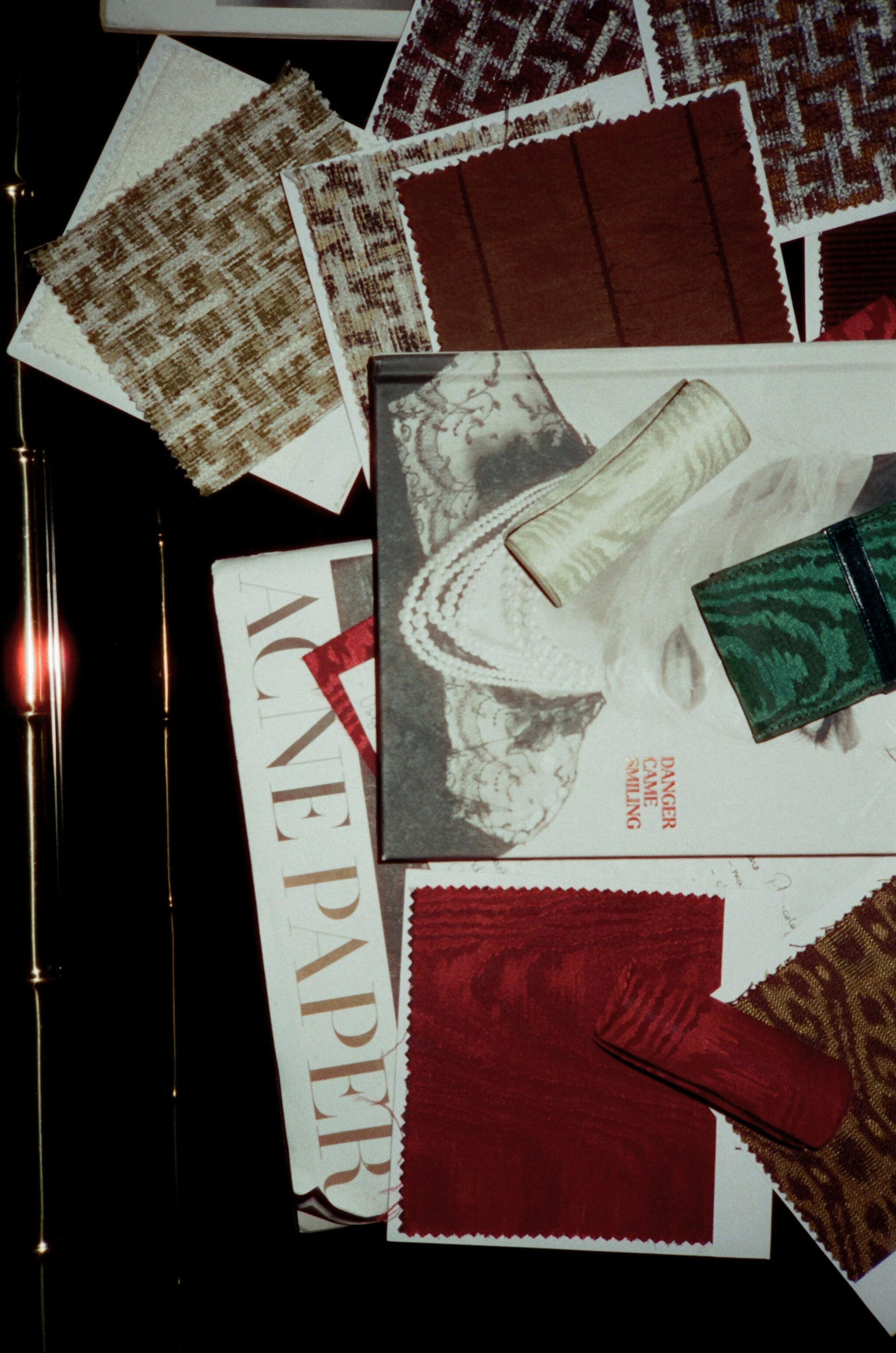 Collection of fabric swatches and a newspaper on a dark surface,  available  to buy on the-salon.com. SALON curates the finest , unique, handmade pieces from the interior industry's best makers and brands. Shop luxury furniture, lighting, rugs, art, antiques and vintage pieces and accessories from SALON interior designed rooms.