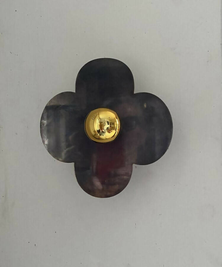 A wall light fixture with a gold-colored top and black, quatrefoil-shaped base,  available  to buy on the-salon.com. SALON curates the finest , unique, handmade pieces from the interior industry's best makers and brands. Shop luxury furniture, lighting, rugs, art, antiques and vintage pieces and accessories from SALON interior designed rooms.
