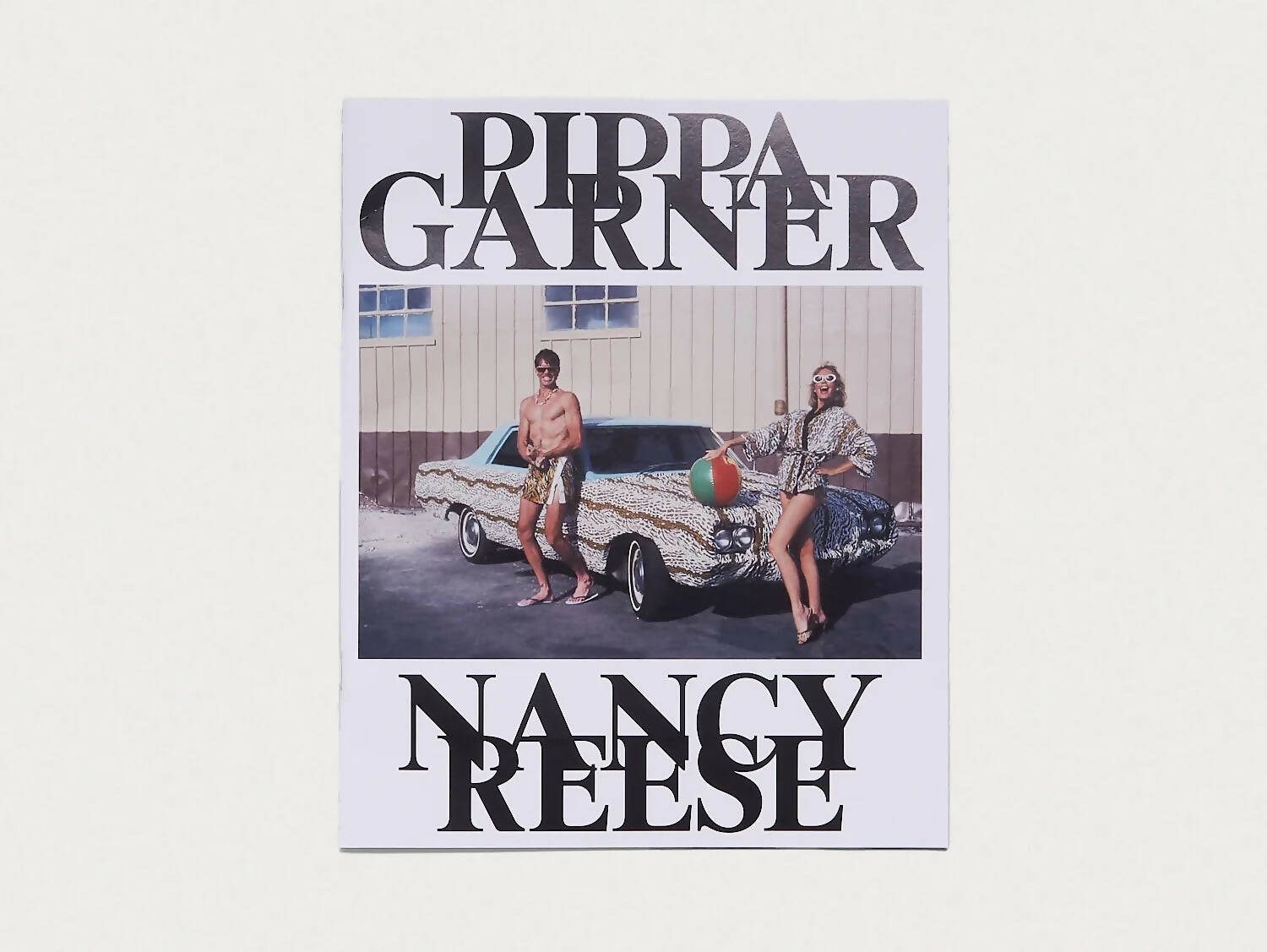Cover of the book 'NANCY REESE' by Antenne Books featuring two individuals sitting on the hood of a car with a focus on the title text, available  to buy on the-salon.com. SALON curates the finest , unique, handmade pieces from the interior industry's best makers and brands. Shop luxury furniture, lighting, rugs, art, antiques and vintage pieces and accessories from SALON interior designed rooms.