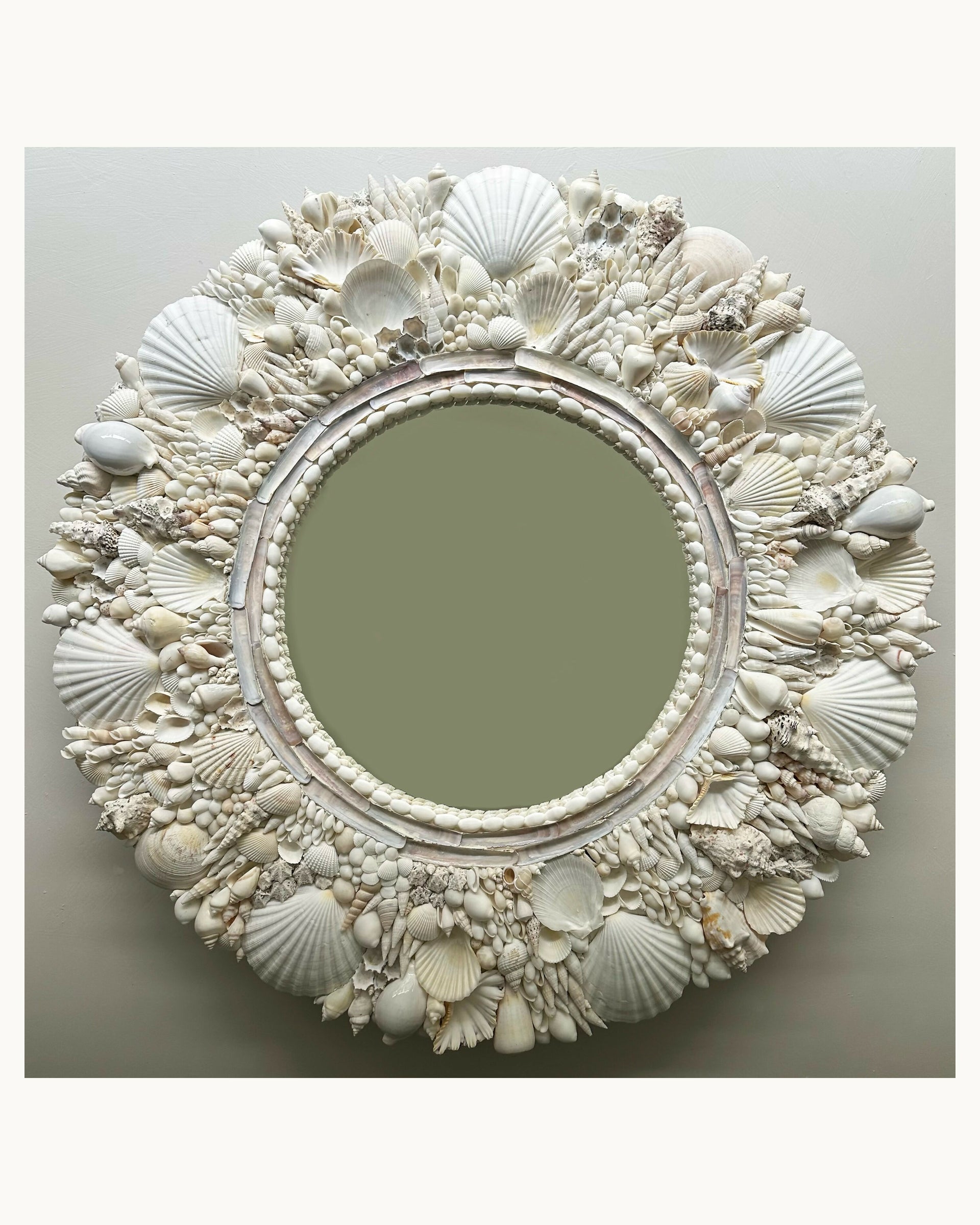 Decorative mirror with seashell frame on a light gray background,  available  to buy on the-salon.com. SALON curates the finest , unique, handmade pieces from the interior industry's best makers and brands. Shop luxury furniture, lighting, rugs, art, antiques and vintage pieces and accessories from SALON interior designed rooms.