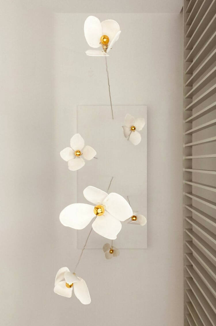 A close-up image of a white magnolia flower pendant light with a brass fitting and a gold-topped SES lamp,  available  to buy on the-salon.com. SALON curates the finest , unique, handmade pieces from the interior industry's best makers and brands. Shop luxury furniture, lighting, rugs, art, antiques and vintage pieces and accessories from SALON interior designed rooms.