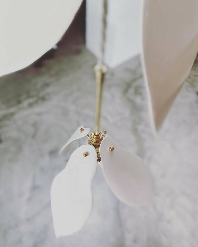 A close-up image of a white magnolia flower pendant light with a brass fitting and a gold-topped SES lamp,  available  to buy on the-salon.com. SALON curates the finest , unique, handmade pieces from the interior industry's best makers and brands. Shop luxury furniture, lighting, rugs, art, antiques and vintage pieces and accessories from SALON interior designed rooms.