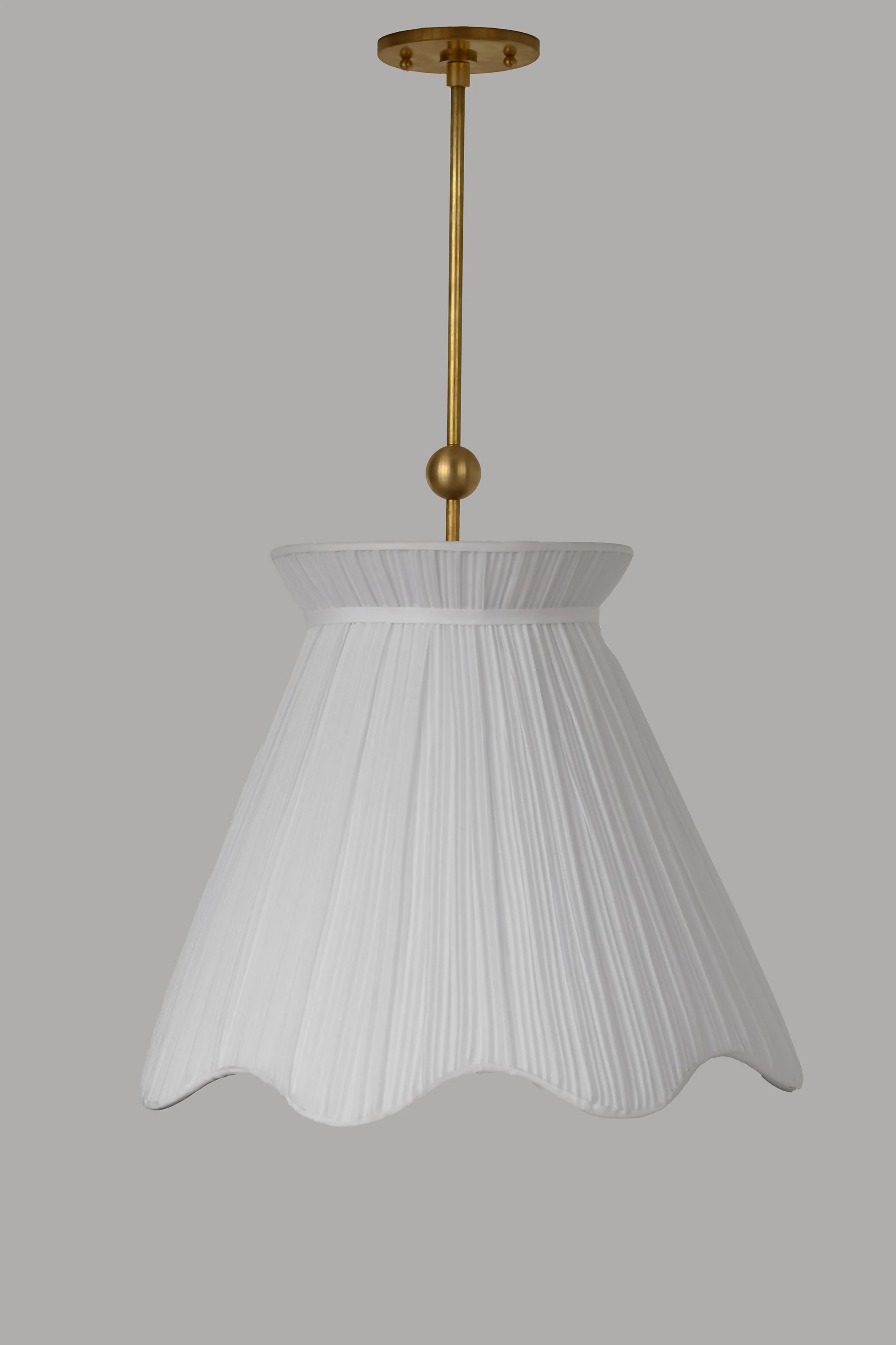A white pleated pendant light hanging in a room with decorative walls, displaying a soft illumination, available  to buy on the-salon.com. SALON curates the finest , unique, handmade pieces from the interior industry's best makers and brands. Shop luxury furniture, lighting, rugs, art, antiques and vintage pieces and accessories from SALON interior designed rooms.
