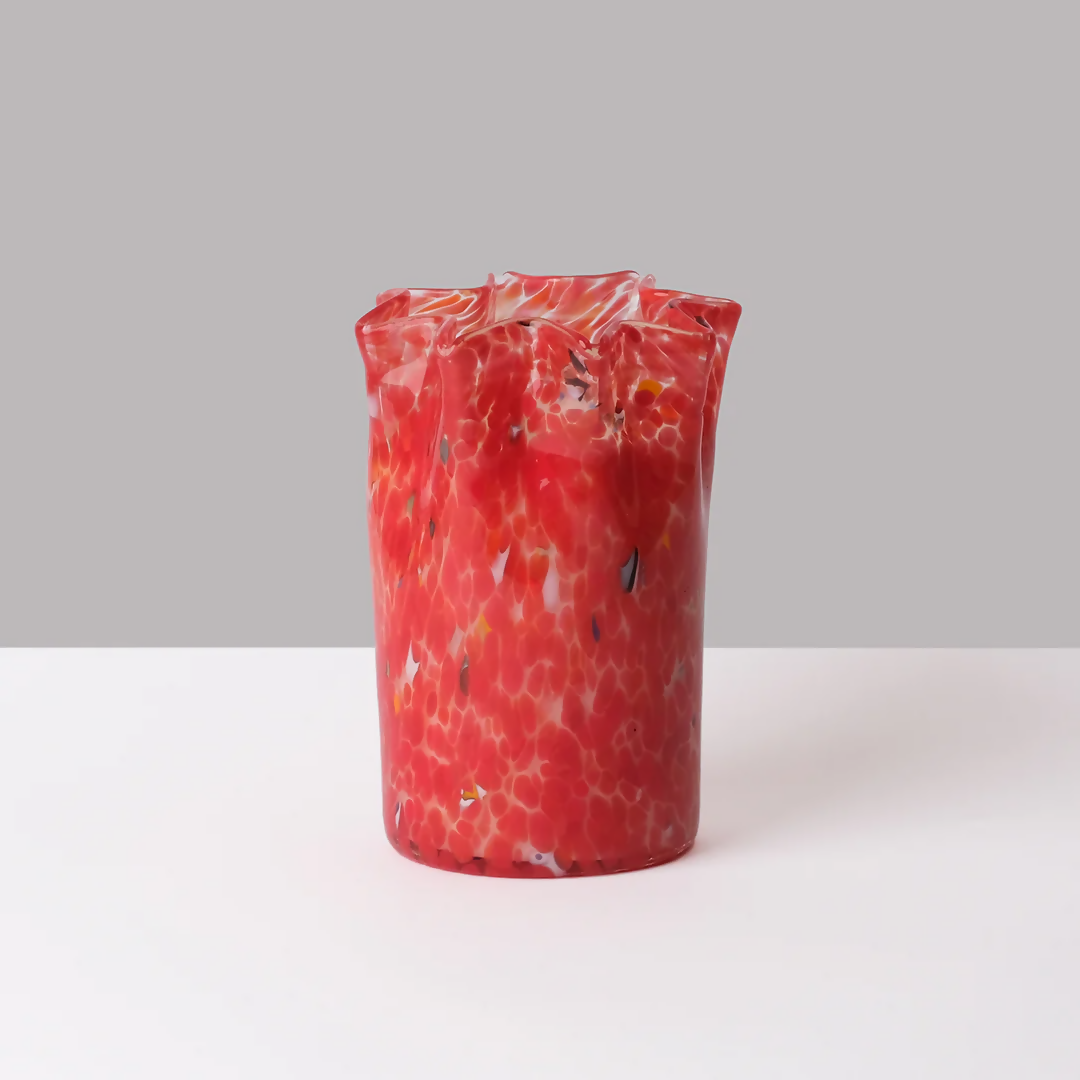 A custom hand-blown red glass candle with a geometric pattern, containing a scented wax and a wick, displayed on a white surface,  available  to buy on the-salon.com. SALON curates the finest , unique, handmade pieces from the interior industry's best makers and brands. Shop luxury furniture, lighting, rugs, art, antiques and vintage pieces and accessories from SALON interior designed rooms.
