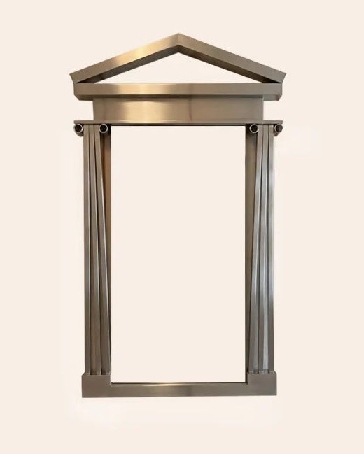 A modern architectural-style wall mirror with a metallic bronze frame and a classical Greek temple pediment design on the top, set against a solid light beige background.