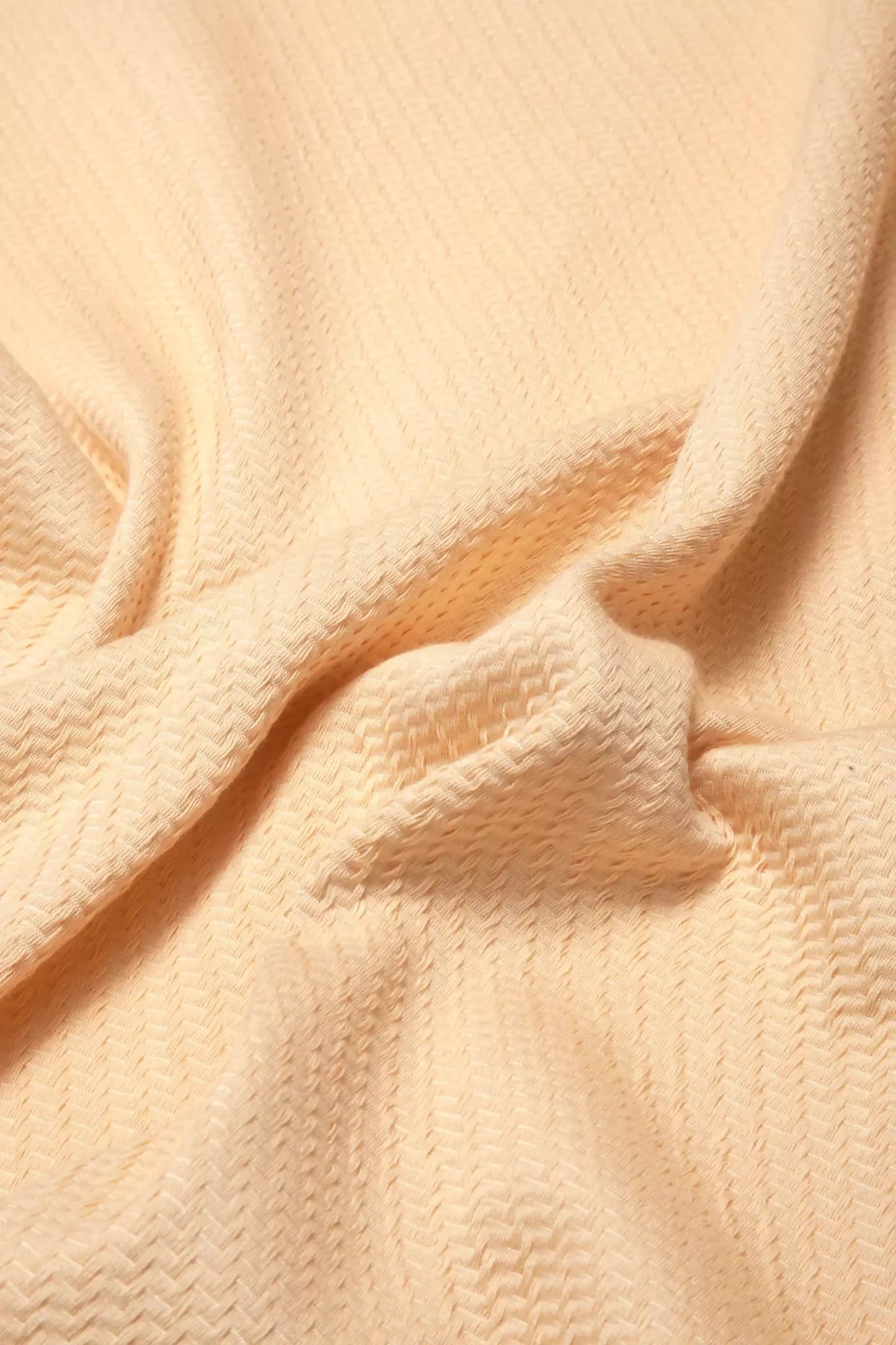 A close-up image of a beige fabric with a textured weave, showcasing its glossy and detailed aspects,  available  to buy on the-salon.com. SALON curates the finest , unique, handmade pieces from the interior industry's best makers and brands. Shop luxury furniture, lighting, rugs, art, antiques and vintage pieces and accessories from SALON interior designed rooms.
