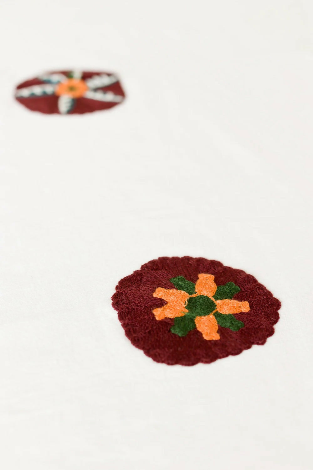 Decorative emblems with floral patterns on a white tablecloth,  available  to buy on the-salon.com. SALON curates the finest , unique, handmade pieces from the interior industry's best makers and brands. Shop luxury furniture, lighting, rugs, art, antiques and vintage pieces and accessories from SALON interior designed rooms.