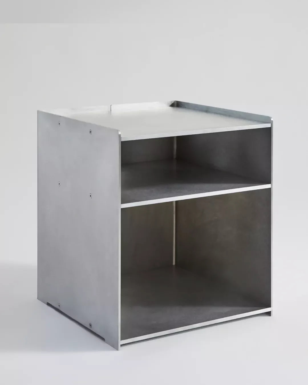 A minimalist silver aluminum media storage cabinet with a hole in the center and multiple shelves,  available  to buy on the-salon.com. SALON curates the finest , unique, handmade pieces from the interior industry's best makers and brands. Shop luxury furniture, lighting, rugs, art, antiques and vintage pieces and accessories from SALON interior designed rooms.