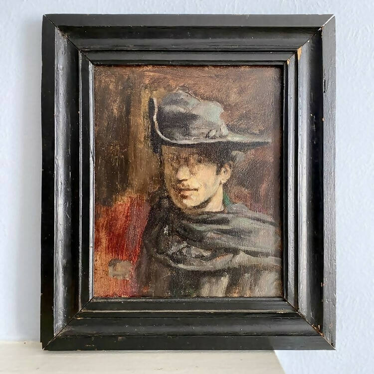 An oil on board painting of a handsome man wearing a classic black hat, with a predominantly black and red colour scheme, framed in a black frame,  available  to buy on the-salon.com. SALON curates the finest , unique, handmade pieces from the interior industry's best makers and brands. Shop luxury furniture, lighting, rugs, art, antiques and vintage pieces and accessories from SALON interior designed rooms.