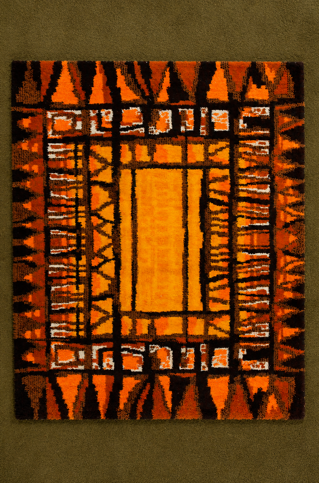 A square woven rug with a bold geometric pattern in orange, black, and white, displayed flat against a textured olive green background.