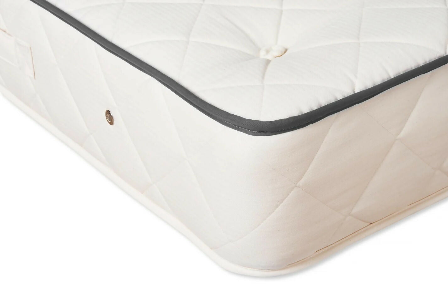 Close-up of a mattress corner with visible stitching on a white background,  available  to buy on the-salon.com. SALON curates the finest , unique, handmade pieces from the interior industry's best makers and brands. Shop luxury furniture, lighting, rugs, art, antiques and vintage pieces and accessories from SALON interior designed rooms.