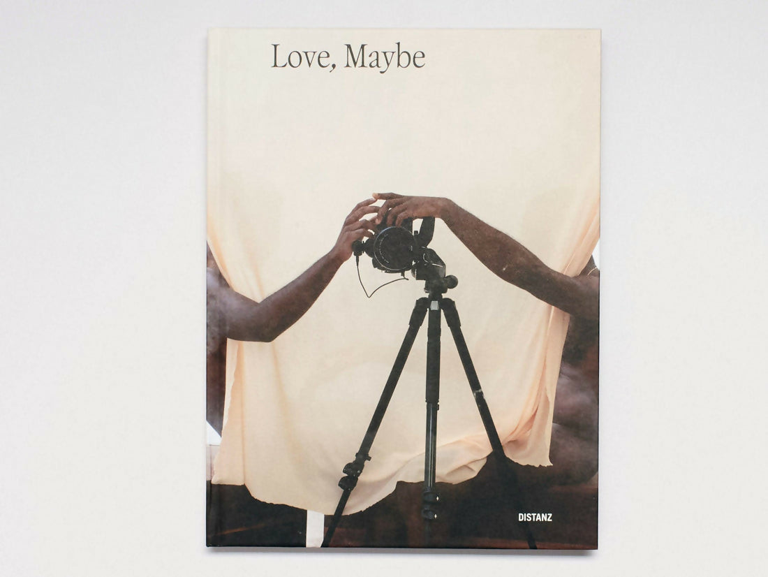 Book cover titled 'Love, Maybe' with two hands reaching towards a camera on a tripod,  available  to buy on the-salon.com. SALON curates the finest , unique, handmade pieces from the interior industry's best makers and brands. Shop luxury furniture, lighting, rugs, art, antiques and vintage pieces and accessories from SALON interior designed rooms.