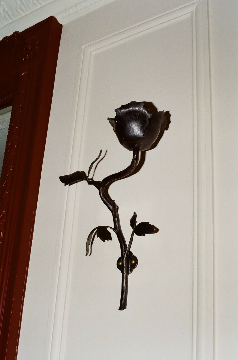A wall-mounted black iron candle sconce in the shape of a clematis flower,  available  to buy on the-salon.com. SALON curates the finest , unique, handmade pieces from the interior industry's best makers and brands. Shop luxury furniture, lighting, rugs, art, antiques and vintage pieces and accessories from SALON interior designed rooms.