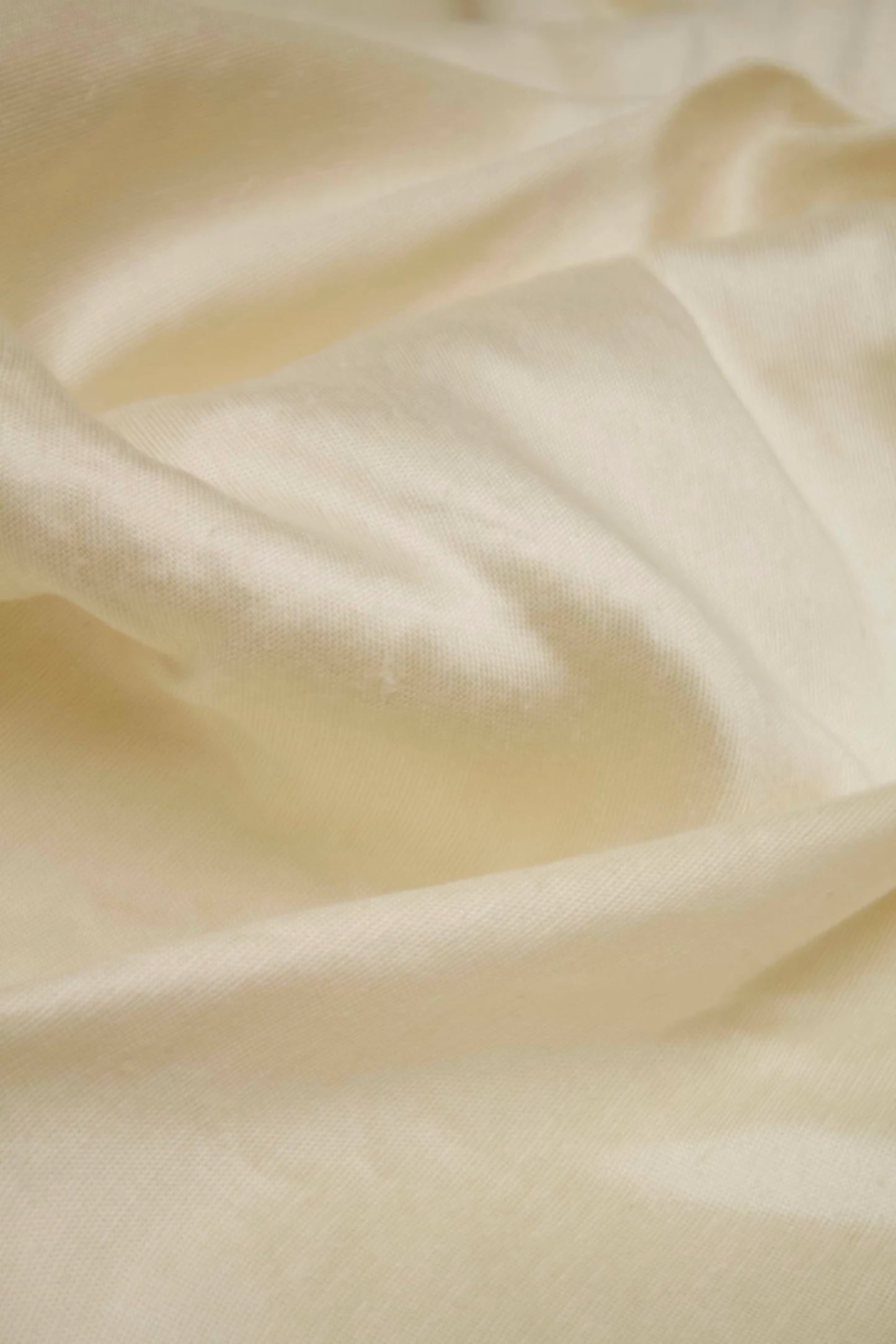 Close-up of a silk sateen fabric in a champagne colour, displaying its texture and sheen,  available  to buy on the-salon.com. SALON curates the finest , unique, handmade pieces from the interior industry's best makers and brands. Shop luxury furniture, lighting, rugs, art, antiques and vintage pieces and accessories from SALON interior designed rooms.