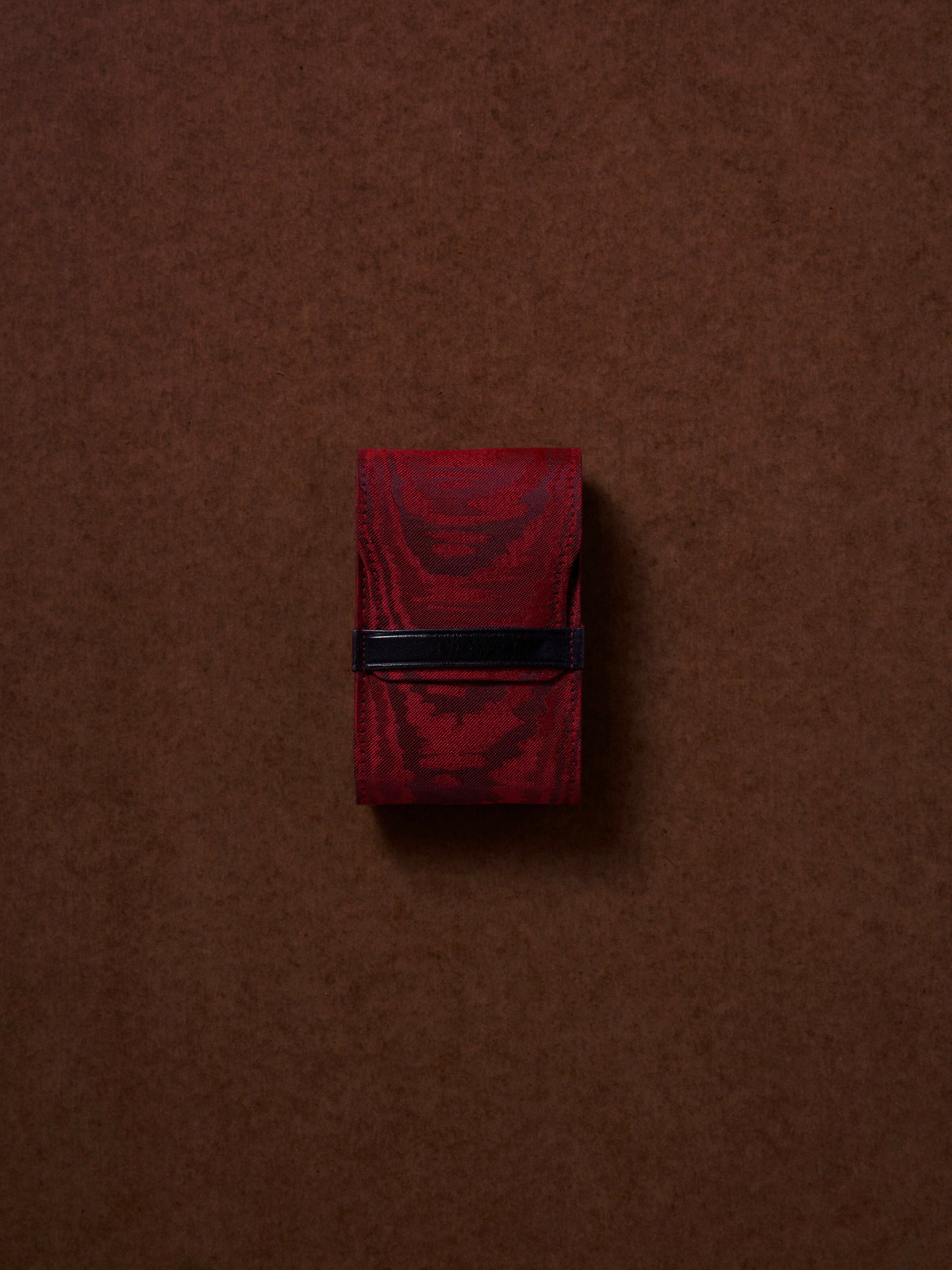 Red fabric folded package on a brown background,  available  to buy on the-salon.com. SALON curates the finest , unique, handmade pieces from the interior industry's best makers and brands. Shop luxury furniture, lighting, rugs, art, antiques and vintage pieces and accessories from SALON interior designed rooms.