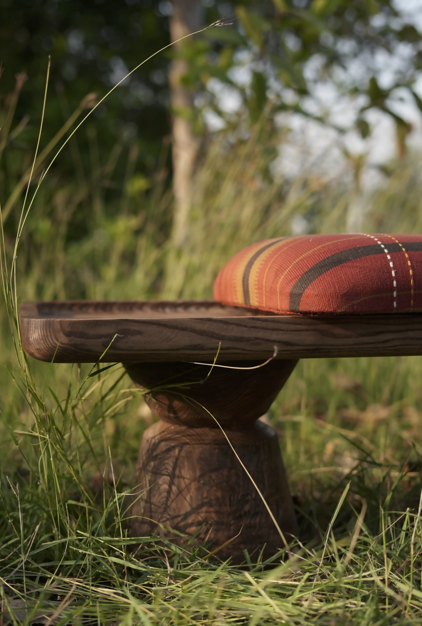 Wooden platform with a cushion in a grassy outdoor setting,  available  to buy on the-salon.com. SALON curates the finest , unique, handmade pieces from the interior industry's best makers and brands. Shop luxury furniture, lighting, rugs, art, antiques and vintage pieces and accessories from SALON interior designed rooms.