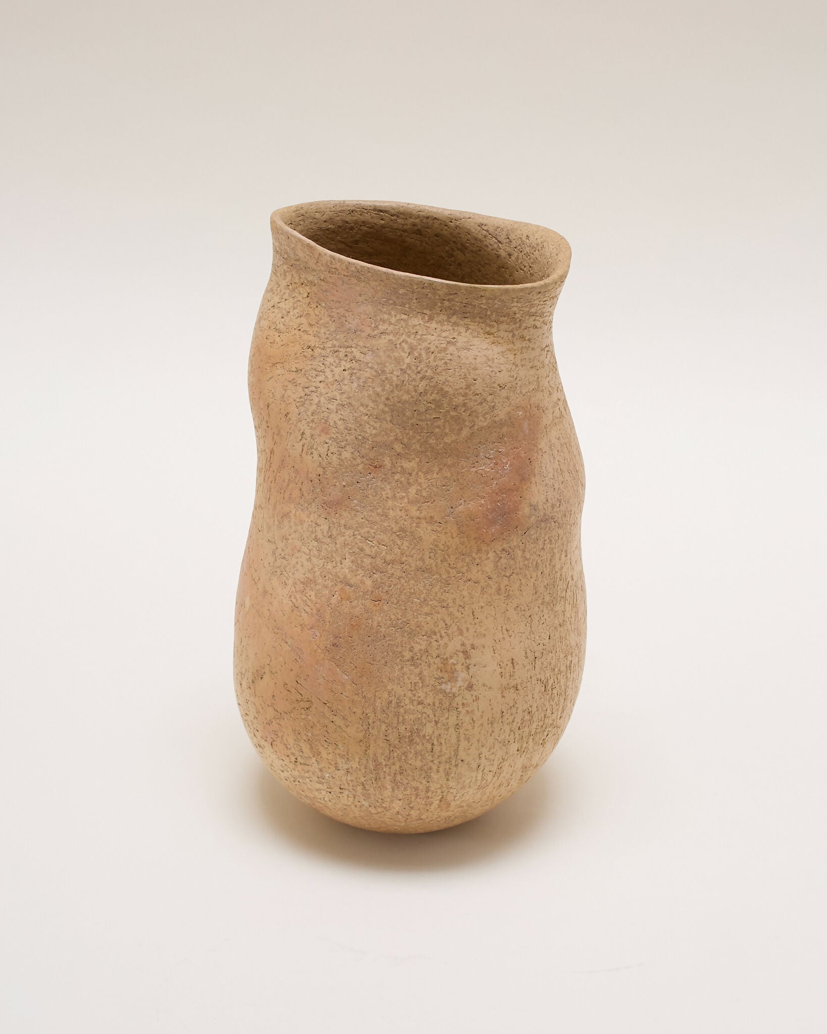 A brown ceramic vase with an organic, irregular silhouette, featuring a smooth yet textured surface with subtle flashes of burnt orange,  available  to buy on the-salon.com. SALON curates the finest , unique, handmade pieces from the interior industry's best makers and brands. Shop luxury furniture, lighting, rugs, art, antiques and vintage pieces and accessories from SALON interior designed rooms.