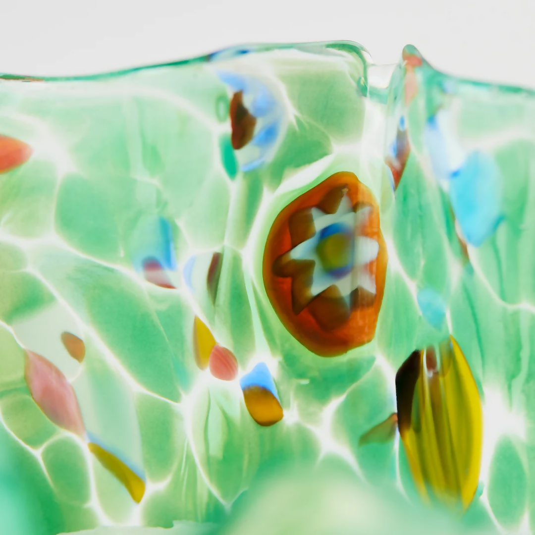 A close up on the detailing on the green glass, showing orange, blue and yellow details within the glass,  available  to buy on the-salon.com. SALON curates the finest , unique, handmade pieces from the interior industry's best makers and brands. Shop luxury furniture, lighting, rugs, art, antiques and vintage pieces and accessories from SALON interior designed rooms.