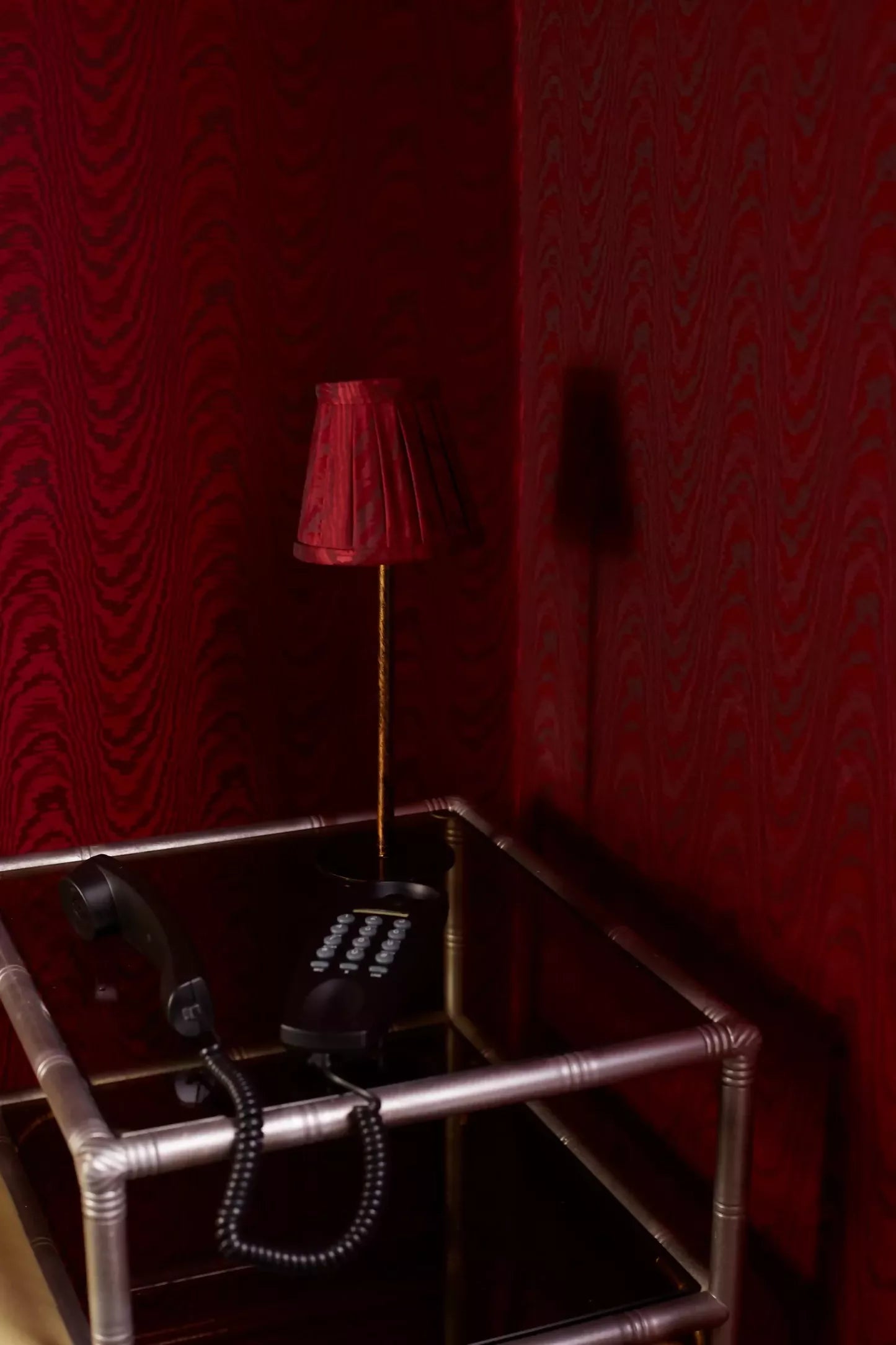 An image of a red moiré patterned fabric on the walls and as a lampshade,  available  to buy on the-salon.com. SALON curates the finest , unique, handmade pieces from the interior industry's best makers and brands. Shop luxury furniture, lighting, rugs, art, antiques and vintage pieces and accessories from SALON interior designed rooms.