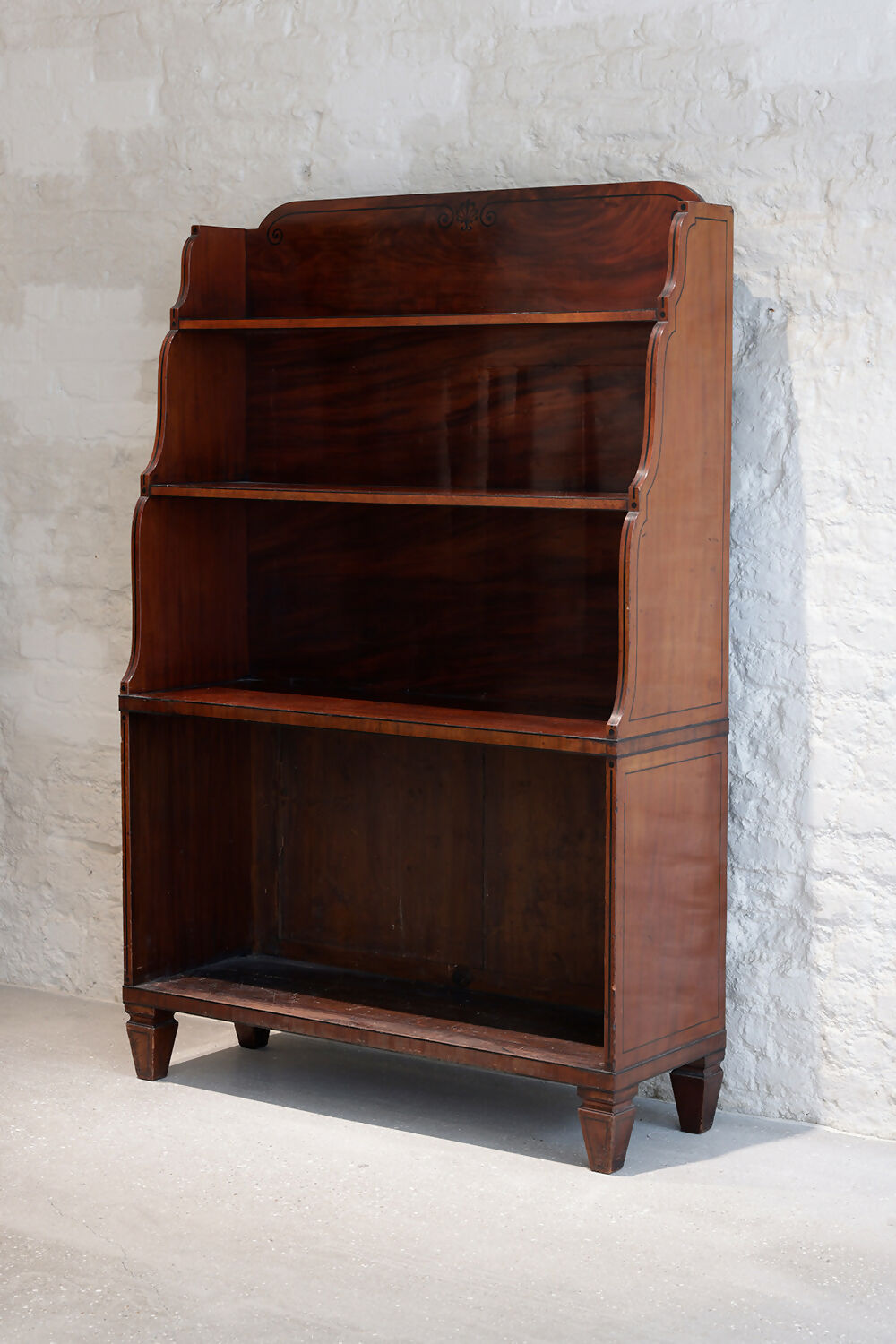A REGENCY MAHOGANY AND EBONY INLAID WATERFALL BOOKCASE