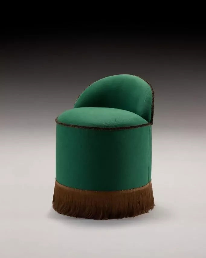 A green upholstered Inferi stool with a curvilinear backrest and a brown fringe at the base, designed for room service or salon use,  available  to buy on the-salon.com. SALON curates the finest , unique, handmade pieces from the interior industry's best makers and brands. Shop luxury furniture, lighting, rugs, art, antiques and vintage pieces and accessories from SALON interior designed rooms.