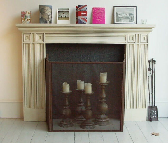 A neo-classical style fireplace made of redwood pine with a metal fire screen and tools in front, set against a white background,  available  to buy on the-salon.com. SALON curates the finest , unique, handmade pieces from the interior industry's best makers and brands. Shop luxury furniture, lighting, rugs, art, antiques and vintage pieces and accessories from SALON interior designed rooms.