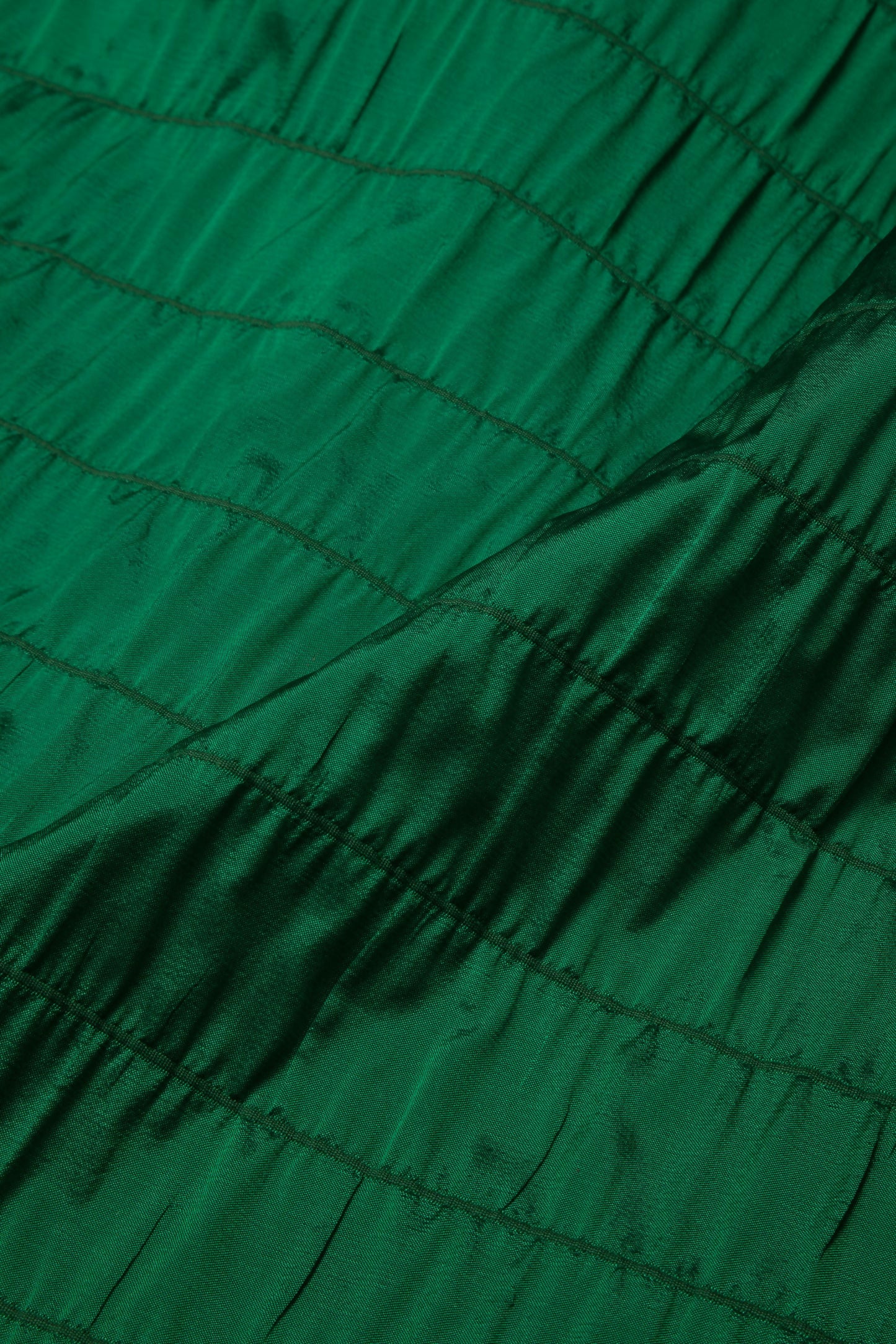 Close-up of a green fabric with a textured design, likely silk, used as a backdrop for painting or creative purposes,  available  to buy on the-salon.com. SALON curates the finest , unique, handmade pieces from the interior industry's best makers and brands. Shop luxury furniture, lighting, rugs, art, antiques and vintage pieces and accessories from SALON interior designed rooms.