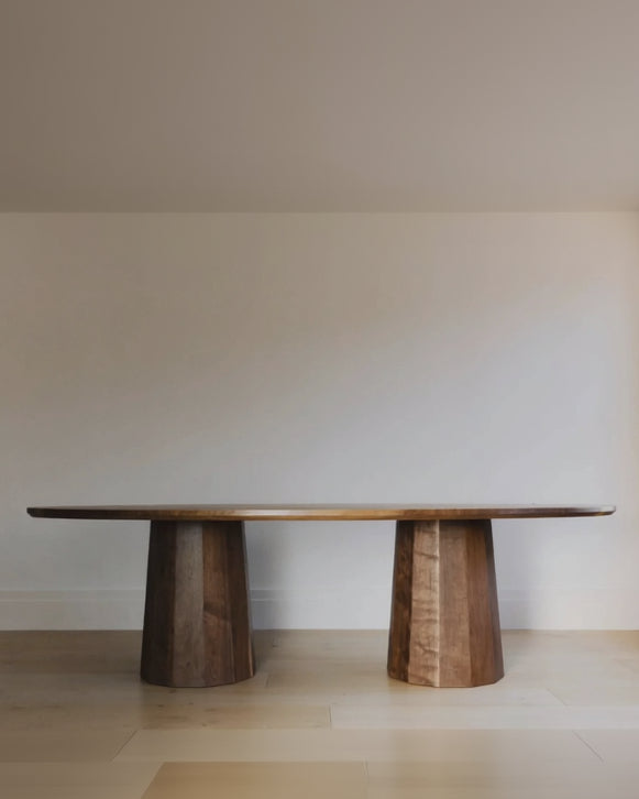 Wooden dining table with two cylindrical legs on a plain background