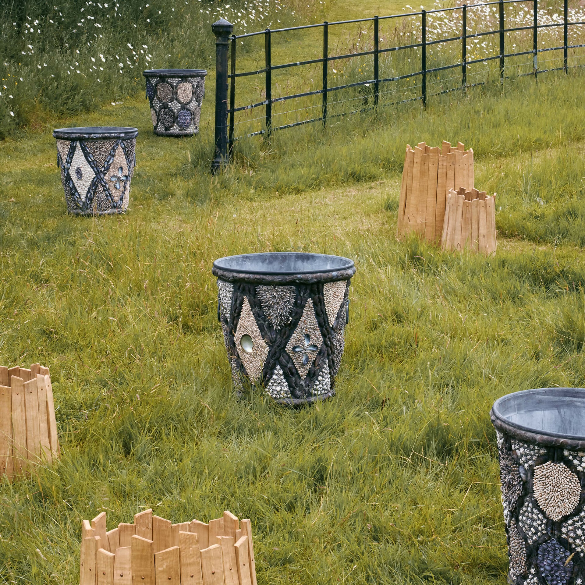 Decorative stone planters with geometric patterns in a grassy field.