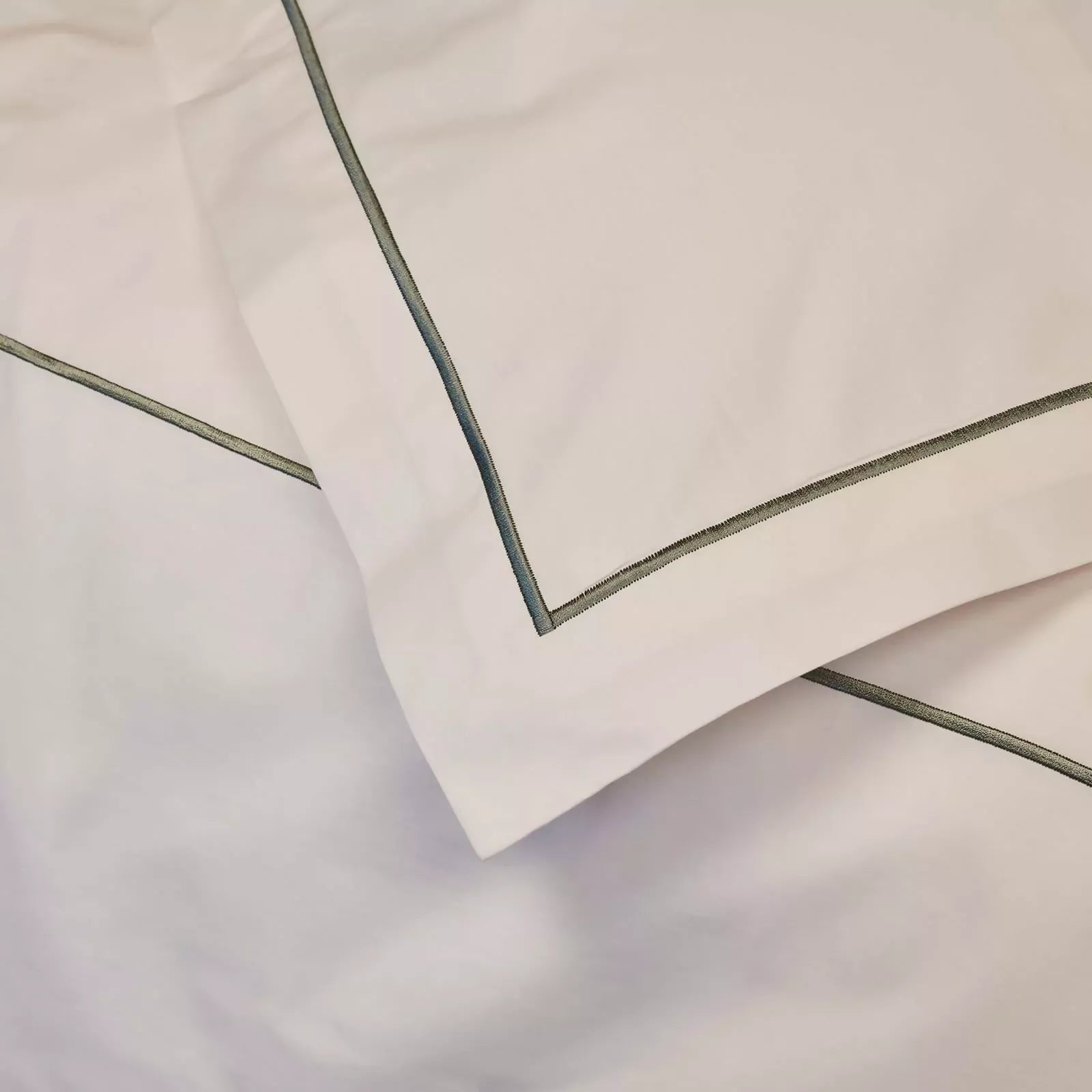 Close-up of beige fabric with green piping on a light gray background,  available  to buy on the-salon.com. SALON curates the finest , unique, handmade pieces from the interior industry's best makers and brands. Shop luxury furniture, lighting, rugs, art, antiques and vintage pieces and accessories from SALON interior designed rooms.