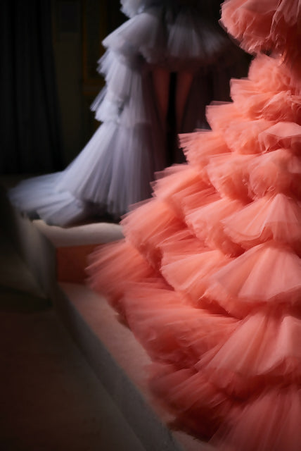 A close-up photograph of a pink tulle detail on a garment, with a blurred background featuring a white tulle detail, available  to buy on the-salon.com. SALON curates the finest , unique, handmade pieces from the interior industry's best makers and brands. Shop luxury furniture, lighting, rugs, art, antiques and vintage pieces and accessories from SALON interior designed rooms.
