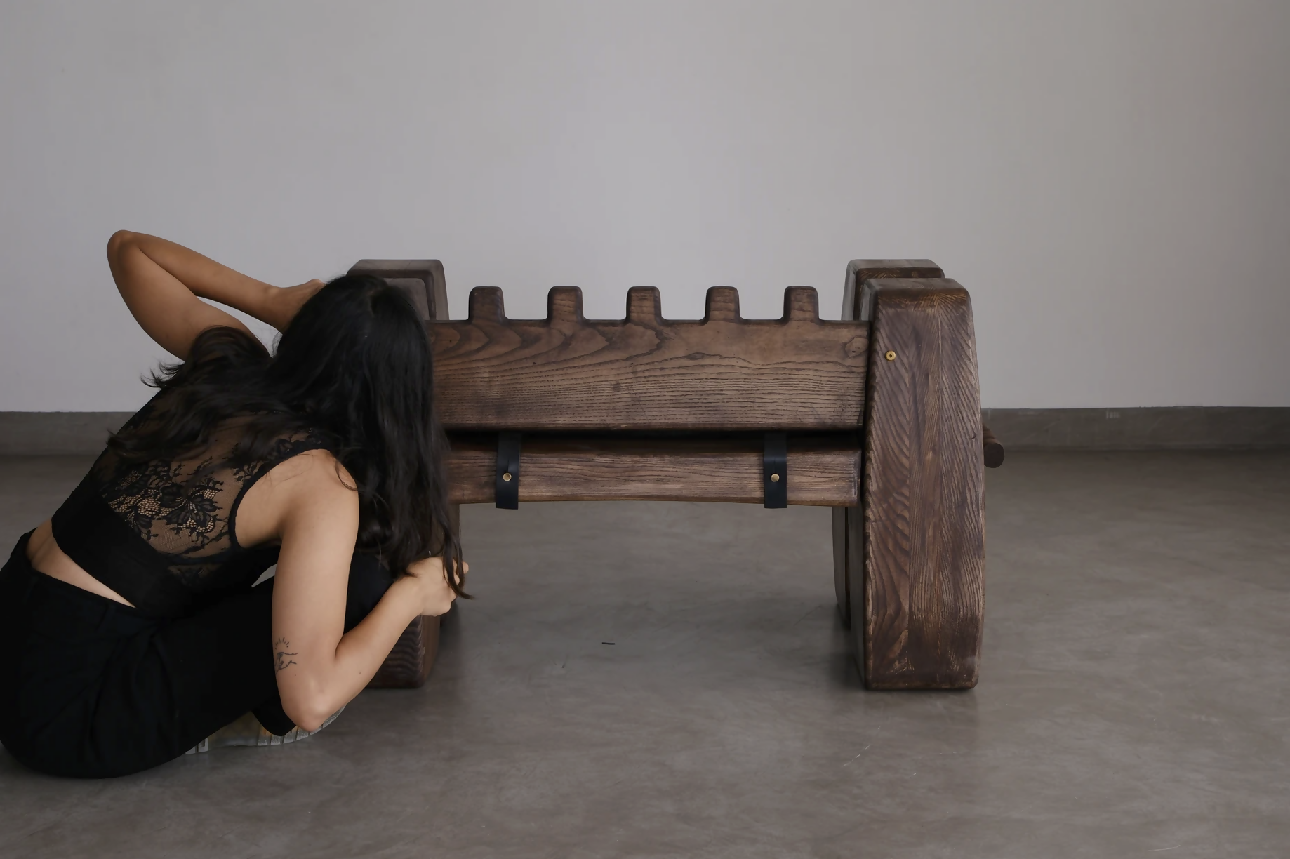 Person in a black dress lying on the floor next to a wooden sculpture,  available  to buy on the-salon.com. SALON curates the finest , unique, handmade pieces from the interior industry's best makers and brands. Shop luxury furniture, lighting, rugs, art, antiques and vintage pieces and accessories from SALON interior designed rooms.