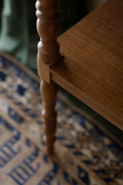 A close up on the wood, on the brown wooden bedside table with a leather top, placed on a patterned carpet,  available  to buy on the-salon.com. SALON curates the finest , unique, handmade pieces from the interior industry's best makers and brands. Shop luxury furniture, lighting, rugs, art, antiques and vintage pieces and accessories from SALON interior designed rooms.
