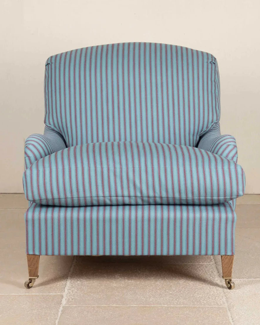 A single upholstered armchair with a light blue and white vertical stripe pattern, shown against a neutral beige wall and tiled floor.
