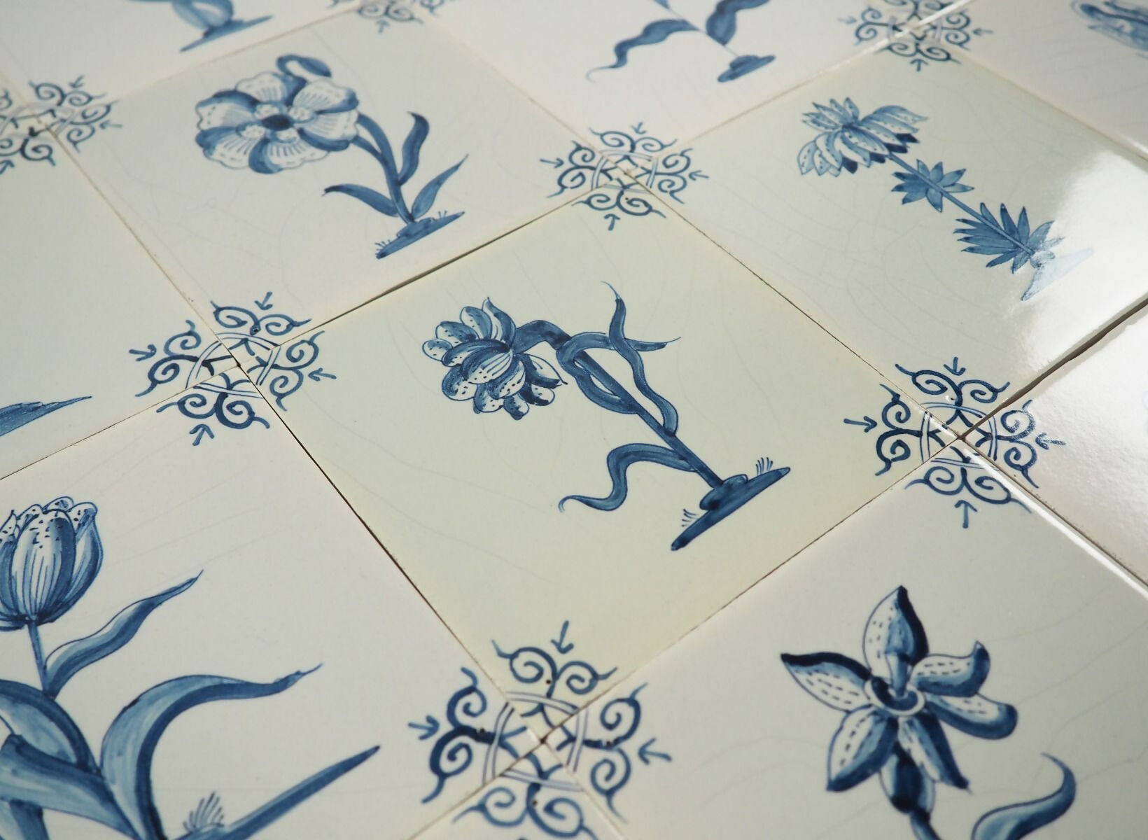 Close-up of ceramic tiles with blue floral and geometric patterns on a white background,  available  to buy on the-salon.com. SALON curates the finest , unique, handmade pieces from the interior industry's best makers and brands. Shop luxury furniture, lighting, rugs, art, antiques and vintage pieces and accessories from SALON interior designed rooms.