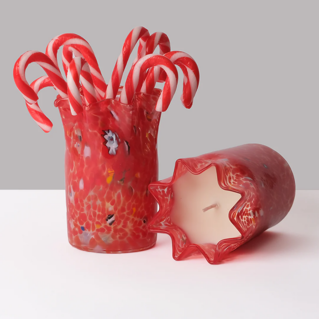 A custom hand-blown red glass candle with a geometric pattern, containing a scented wax and a wick, displayed on a white surface,  available  to buy on the-salon.com. SALON curates the finest , unique, handmade pieces from the interior industry's best makers and brands. Shop luxury furniture, lighting, rugs, art, antiques and vintage pieces and accessories from SALON interior designed rooms.