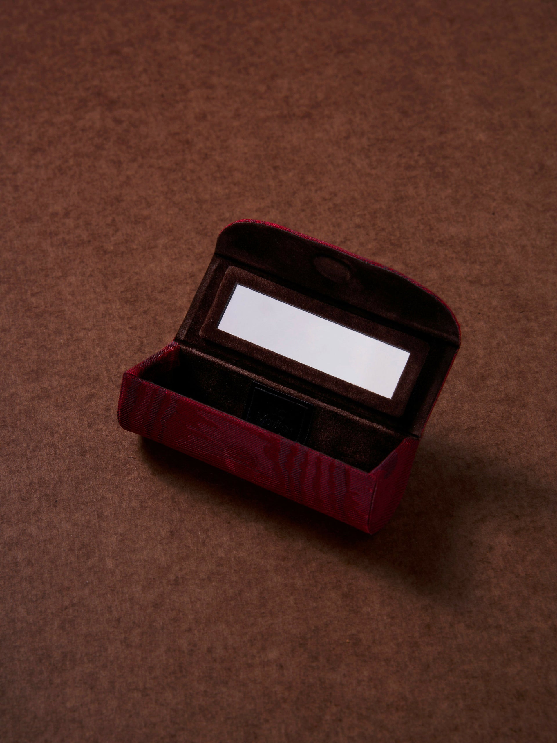 Open red velvet jewelry box on a brown background,  available  to buy on the-salon.com. SALON curates the finest , unique, handmade pieces from the interior industry's best makers and brands. Shop luxury furniture, lighting, rugs, art, antiques and vintage pieces and accessories from SALON interior designed rooms.