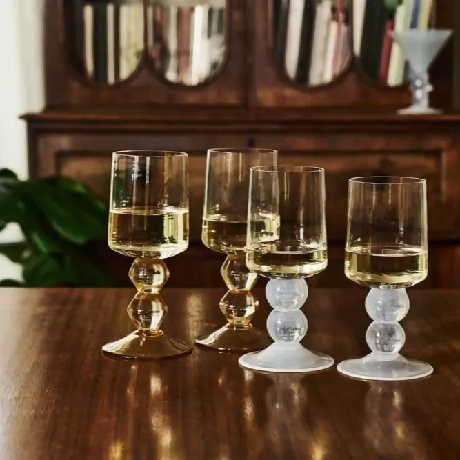 Four glass wine glasses with different bases on a wooden table, available  to buy on the-salon.com. SALON curates the finest , unique, handmade pieces from the interior industry's best makers and brands. Shop luxury furniture, lighting, rugs, art, antiques and vintage pieces and accessories from SALON interior designed rooms.
