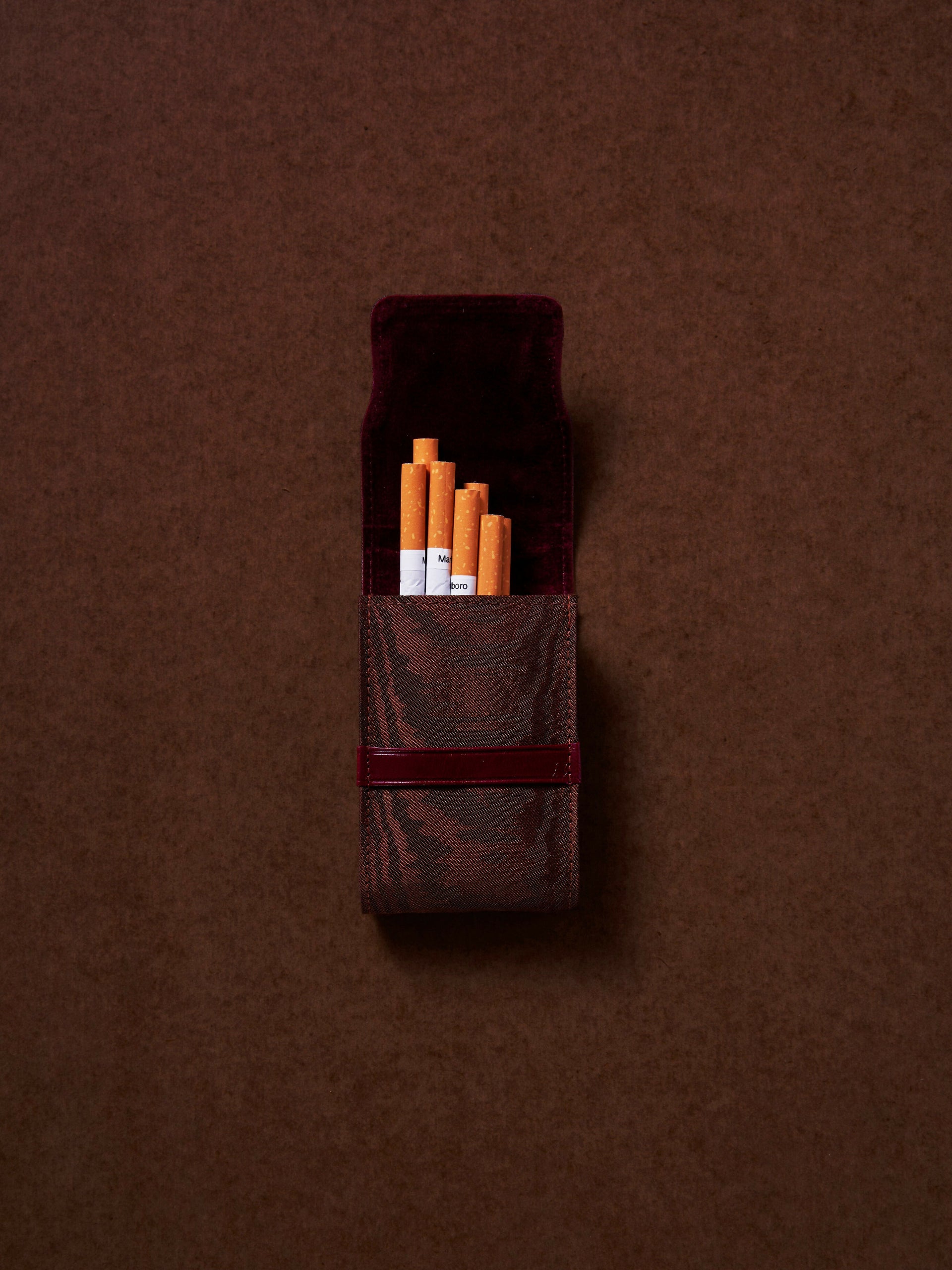 Brown cigarette case with cigarettes on a brown background,  available  to buy on the-salon.com. SALON curates the finest , unique, handmade pieces from the interior industry's best makers and brands. Shop luxury furniture, lighting, rugs, art, antiques and vintage pieces and accessories from SALON interior designed rooms.